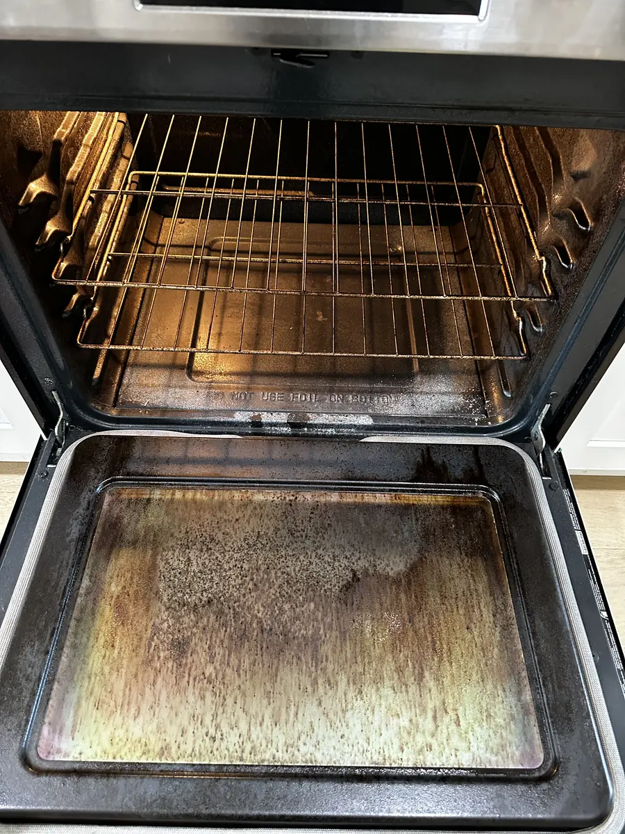 Oven door glass coated in baked-on grease before cleaning